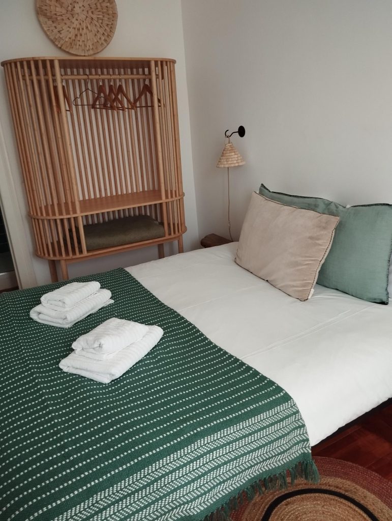 cama muiro bem feita com 2 conjuntos de toalhas brancas por cima